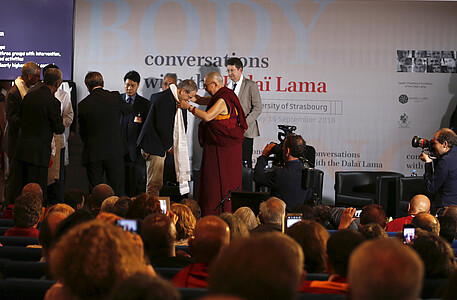 Le Dalaï-Lama passe un khatag autour du cou de ses interlocuteurs, écharpe blanche en soie traditionnelle.